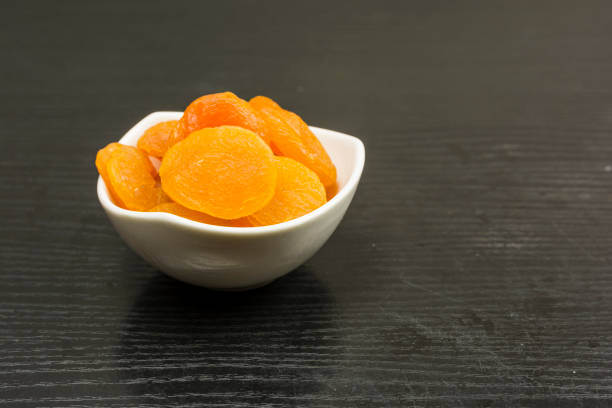 istock A bowl with dried apricots on a dark table. 896802542