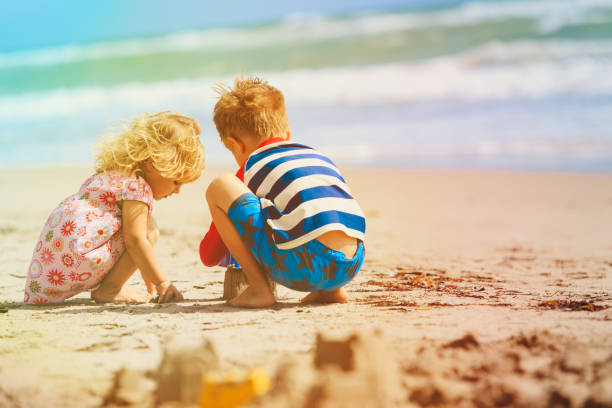 istock little boy and girl play with sand on beach 896808828