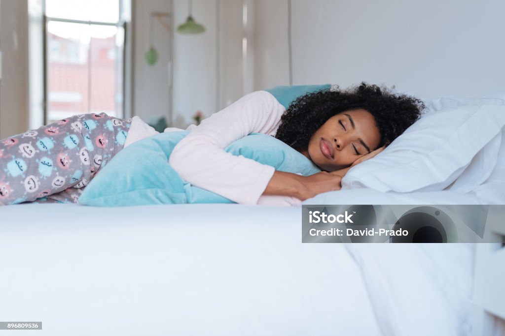 Heureuse belle jeune noire femme couchée dans le lit de couchage « n - Photo de Dormir libre de droits