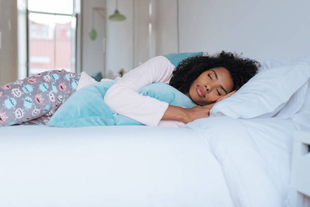 Happy beautiful young black woman lying down in the bed sleeping"n stock photo