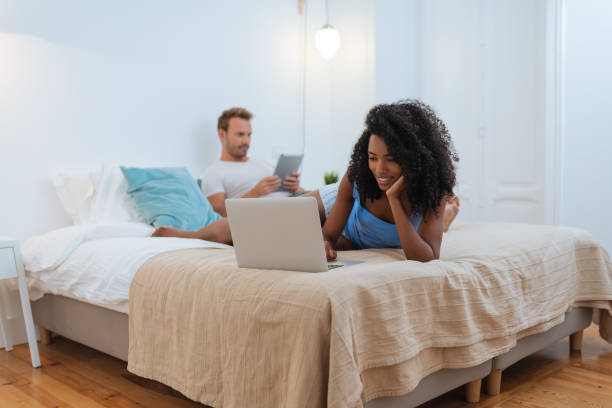 istock Happy young couple relaxed at home lying down in bed on the tablet and computer 
