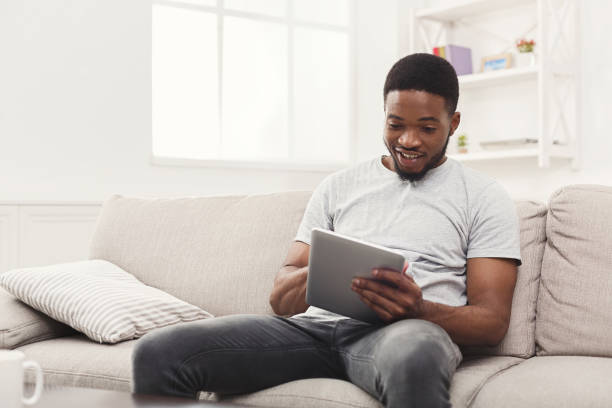 istock Happy young man at home reading on tablet 896822404