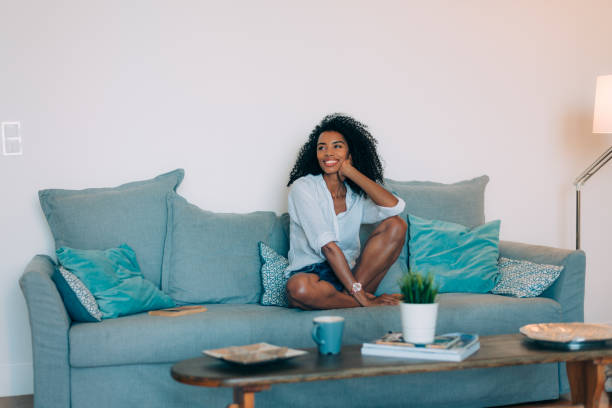 istock Beautiful black young woman seating in the sofa 896825626