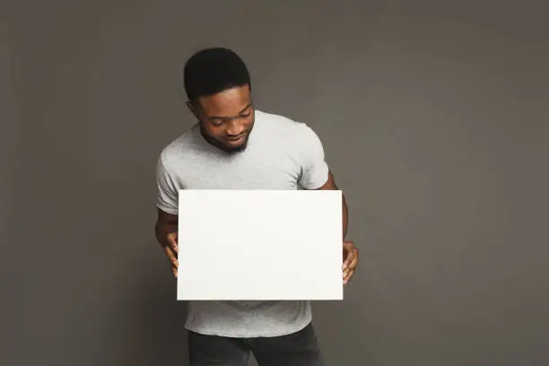 Photo of Picture of young african-american man holding white blank board