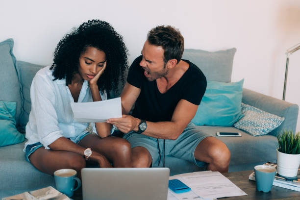 istock Young interracial couple in the couch stressed with financial problems doing calculations with paper work