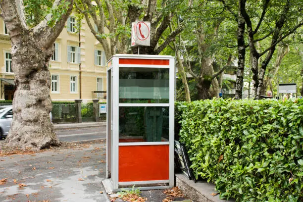 Photo of Public telephone on pathway beside traffic road in small alley for people use phone at Meran, Italy