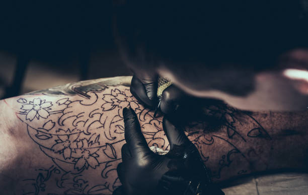 istock Tattoo master making tattoo on customer's leg 896842204