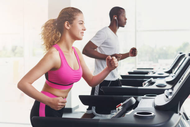 hombre y mujer, pareja de gimnasio caminadoras - couple young adult african descent multi ethnic group fotografías e imágenes de stock