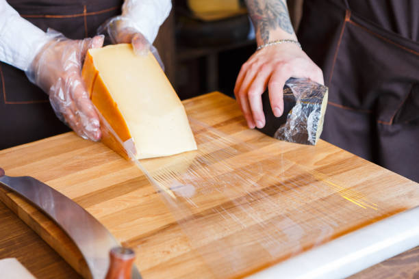 istock Shop assistant wrapping a piece of cheese 896880462
