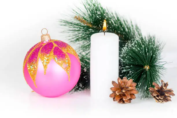 white burning candle and pink xmas bauble, christmas composition isolated on white