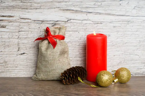 red candle with christmas tree decorations and gift bag
