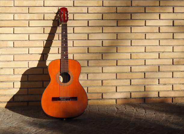 istock Classical guitar on sidewalk and resting on a yellow brick wall 896897686