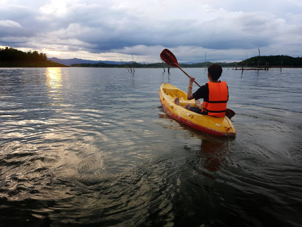 istock Man on kayak with sunset, dramatic sky and cloudy 896903056
