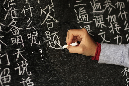girl writing Chinese characters on a blackboard at a remote school in Northern Thailand, Southeast Asia.