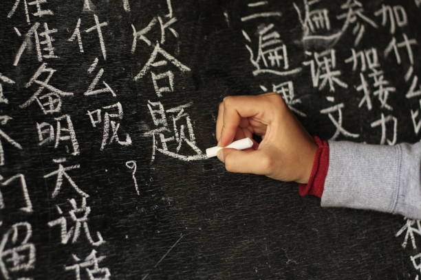 girl writing Chinese characters on a blackboard at a remote school in Northern Thailand girl writing Chinese characters on a blackboard at a remote school in Northern Thailand, Southeast Asia. chinese language stock pictures, royalty-free photos & images