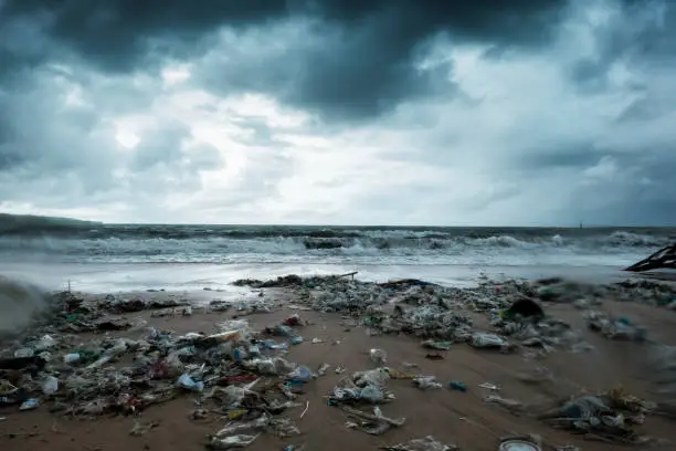 Photo of Garbage on beach, environmental pollution in Bali Indonesia. Storm is coming. And drops of water are on camera lens