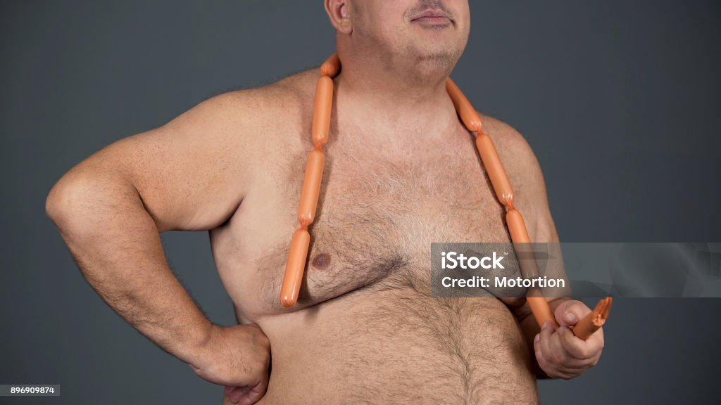 Chubby man eating sausages with appetite, food addiction, risk of diabetes Chubby man eating sausages with appetite, food addiction, risk of diabetes, stock footage Hot Dog Stock Photo