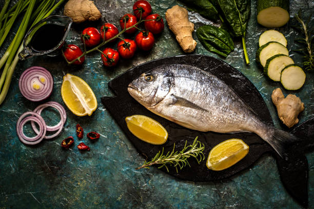 istock Dorada fish with vegetables, lemon and herbs on a blue background 896915816
