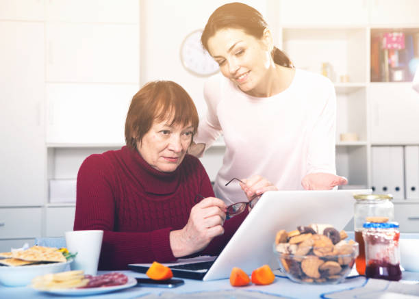 istock Woman at tea table using laptop with mature mother 896919532
