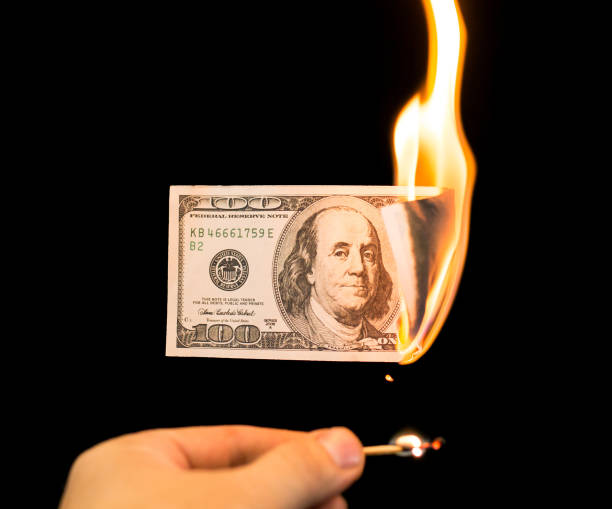 istock a hundred dollars burn in a fire on a black background 896919846