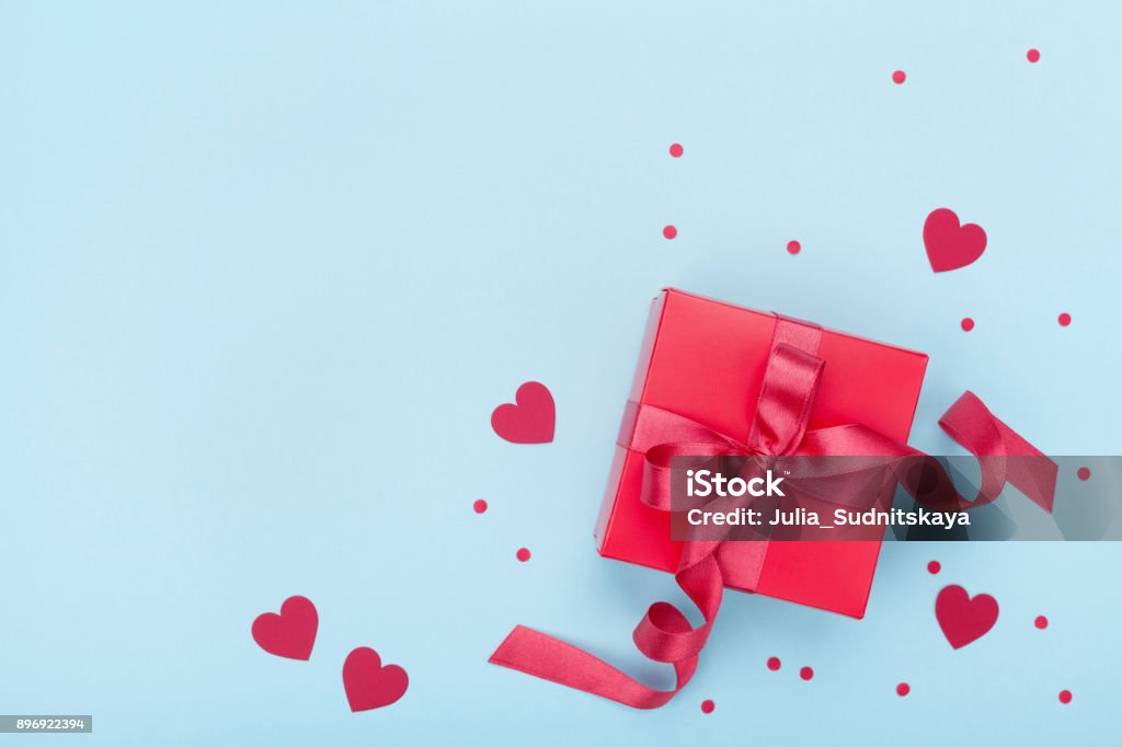 Present or gift box, paper heart and confetti on blue background top view. Valentines day greeting card. Present or gift box, paper heart and confetti on blue background top view. Valentines day greeting card. Flat lay style. Valentine's Day - Holiday Stock Photo