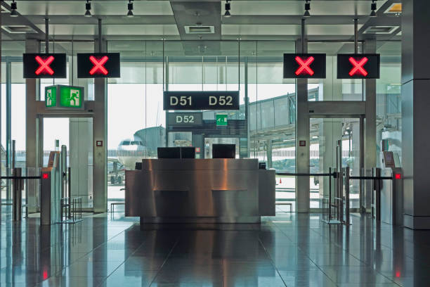 Airport departure lounge gates closed Modern airport departure check in gates closed with red X signs above and an aircraft on the runway. delayed sign photos stock pictures, royalty-free photos & images