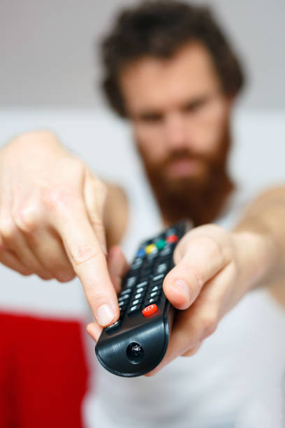 istock Young man watching TV with remote in hand 896926716