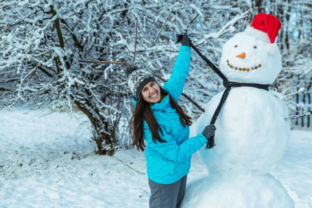 istock woman making snowman in winter day 896933554