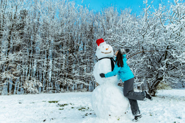 istock woman making snowman in winter day 896933700