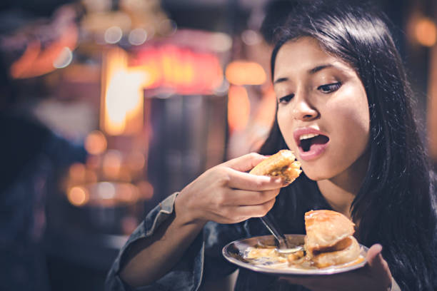 Young woman enjoying street food. Outdoor image of Asian young woman enjoying street food at evening. One person, waist up and selective focus with copy space. himachal pradesh photos stock pictures, royalty-free photos & images