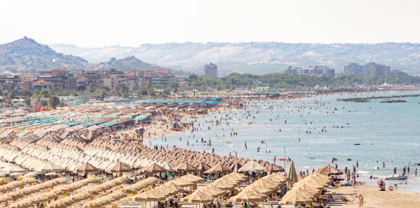 giornata di sole sulla spiaggia di pescara. enorme spiaggia piena di persone e ombrelloni, abruzzo, italia - pescara foto e immagini stock