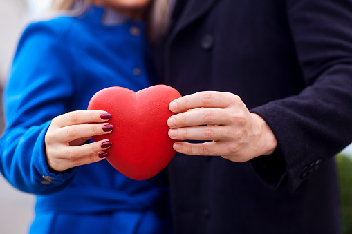The hands of the couple hold a close-up heart in their hands. Concept Valentine's Day.