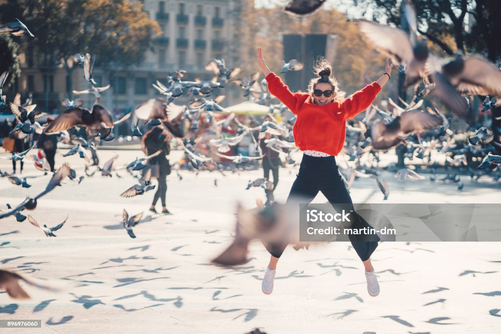 Girl jumping from joy in Barcelona Young girl at Placa de Catalunya jumping happily among the pigeons Ecstatic Stock Photo