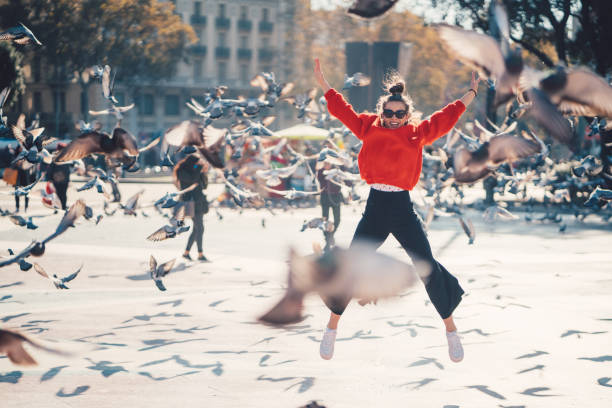 Girl jumping from joy in Barcelona Young girl at Placa de Catalunya jumping happily among the pigeons pigeon photos stock pictures, royalty-free photos & images