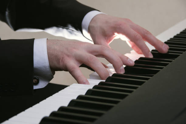 male's hand playing a piano in dramatic lighting