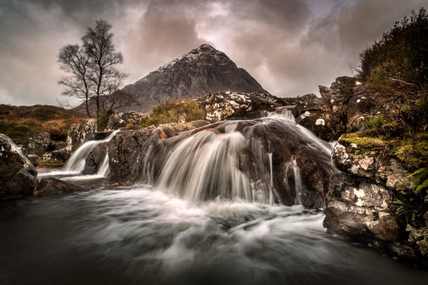 River Coupal and Buachaille Etive Mor, Glencoe, Scotland. A long exposure waterfall beneath a mountain called Buachaille Etive Mor. A tree stands to the left of the waterfall buachaille etive mor photos stock pictures, royalty-free photos & images