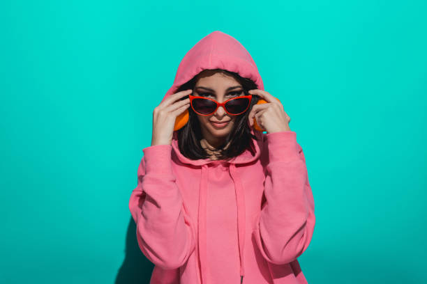 istock Young woman holding an orange while standing by a blue color background 897020312