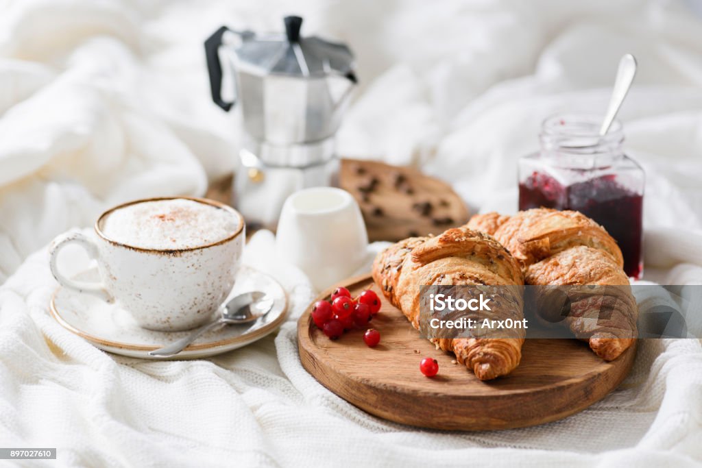 Breakfast in bed with croissants, coffee and jam Breakfast in bed with croissants, jam, coffee cappucino with cream and milk foam. Horizontal view Breakfast Stock Photo