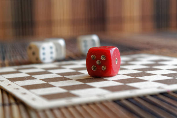 istock Stack of three white plastic dices and one red dice on brown wooden board background. Six sides cube with black dots. Number 5 897027626