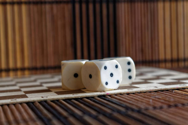 istock Stack of three white plastic dices on brown wooden board background. Six sides cube with black dots. Rundom number 897030040