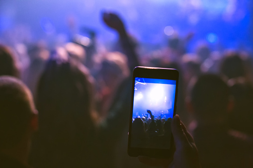 The audience is filming on the smartphone. Concert in the nightclub.