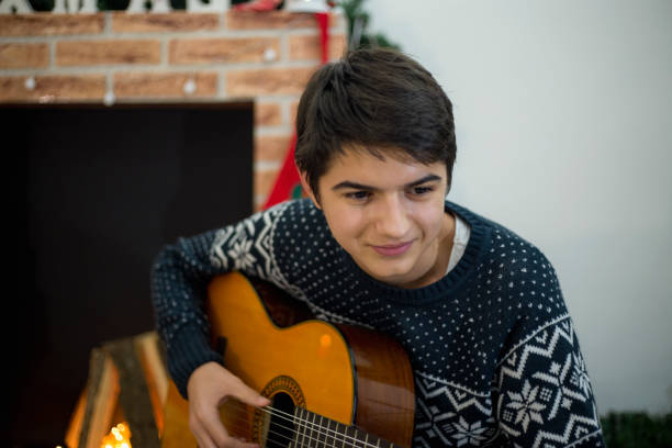 그의 기타 연주와 노래 크리스마스 트리 근처 실내 젊은 남자의 초상화 - suit jeans men musician 뉴스 사진 이미지