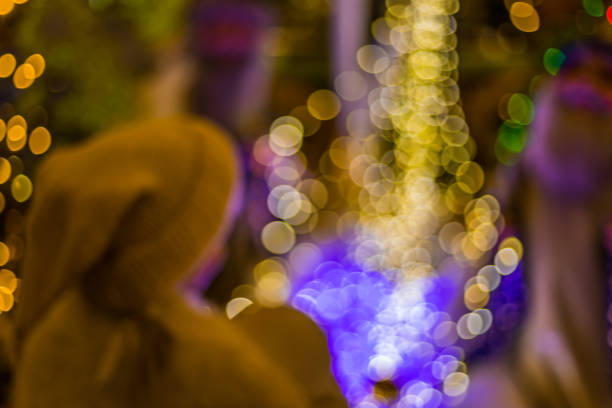 Abstract blurred background with christmas tree, holiday decorations, beautiful light bokeh and personages.