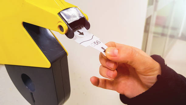 Taking numbered ticket out from dispenser machine Customer pulls with hand a numbered ticket out of yellow number dispenser machine, to wait in service line and to be served when his number is displayed change dispenser stock pictures, royalty-free photos & images