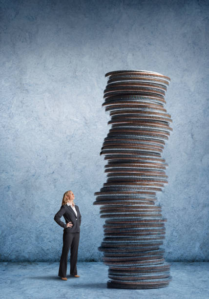 istock Businesswoman Looking Up At Tall Stack Of Coins 897059796