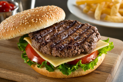 A delicious grilled Angus beef burger with cheese, lettuce, and tomato on a sesame seed bun.