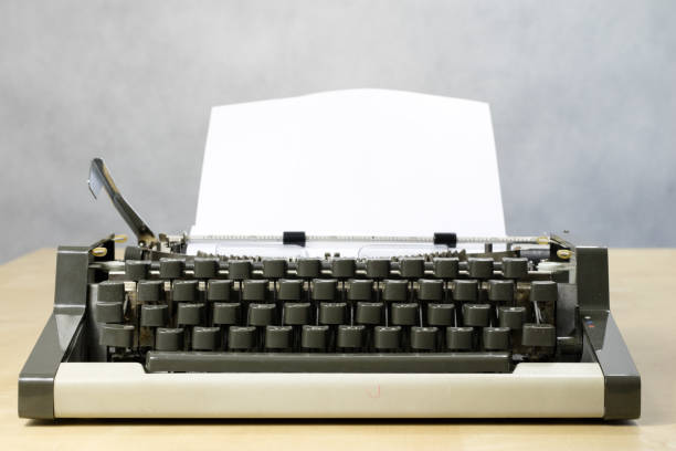 istock Typewriter and white card screwed into the machine. Wooden table with a typewriter. White background. 897060354