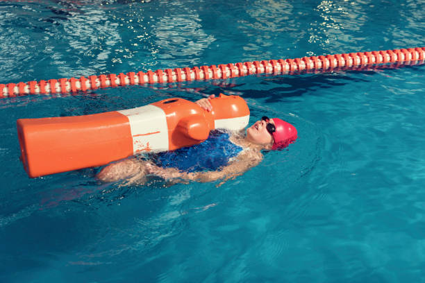 uma garota com boneco em uma piscina de formação - lifeguard - fotografias e filmes do acervo