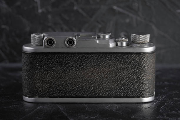 istock Old rangefinder film camera on a black concrete background. 897077650
