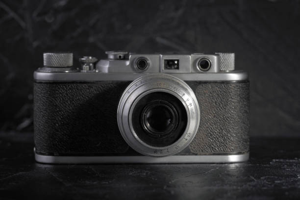 istock Old rangefinder film camera on a black concrete background. 897077656